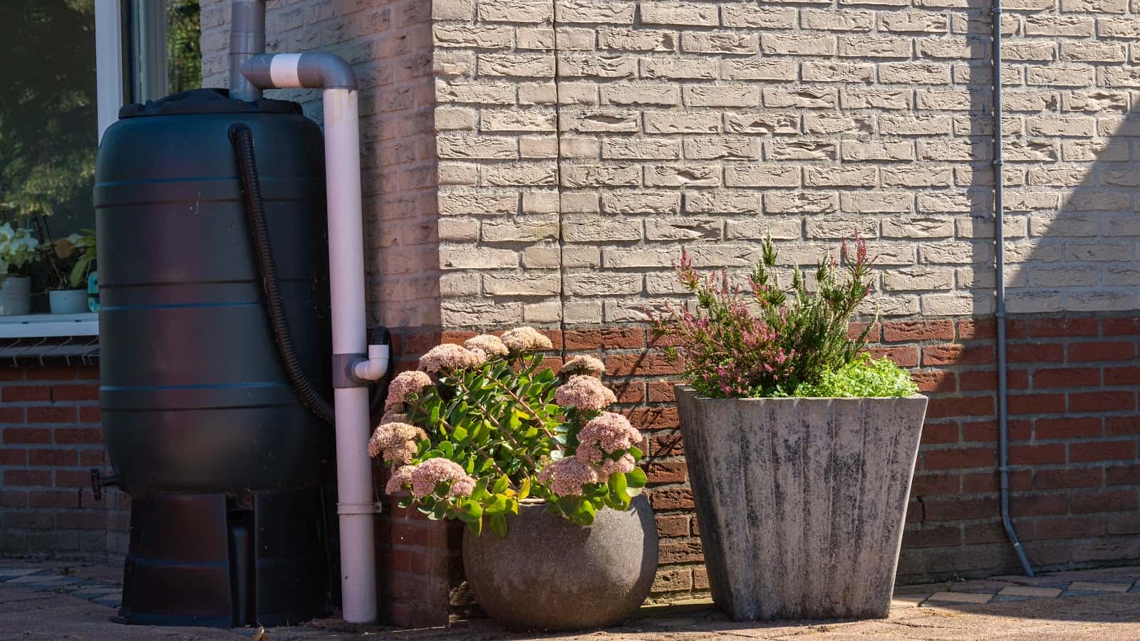 A Black Rainwater Harvesting System On A Home With Brick Siding